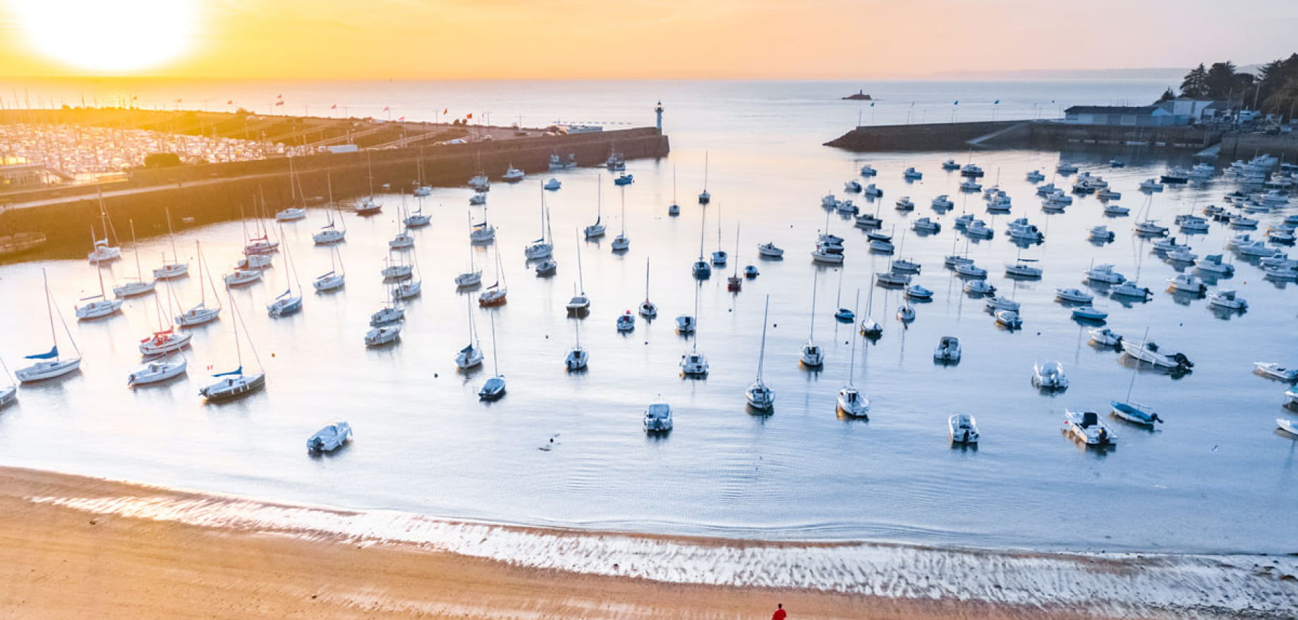Vue drône des ports, un homme est seul sur la plage du Portrieux, regarde le lever de soleil